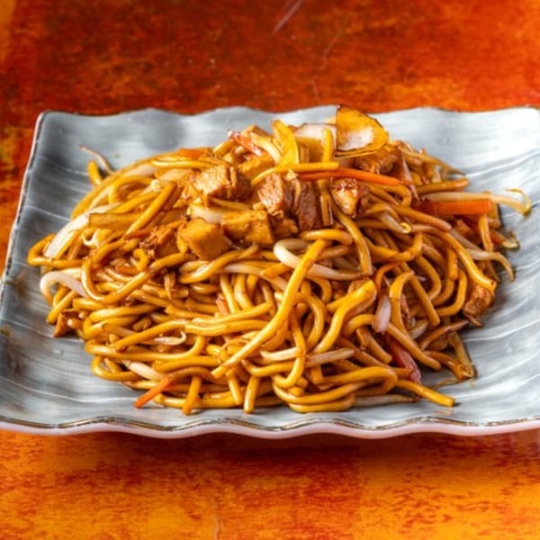 Chow n Joy's chow mein with noodles, chicken, onions, and bean sprouts on a gray plate.