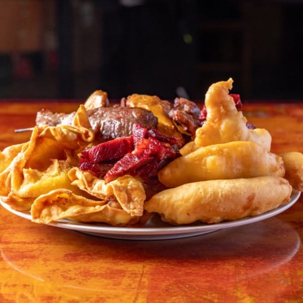 A platter of Chinese appetizers including fried wontons, barbecued pork, and battered shrimp.