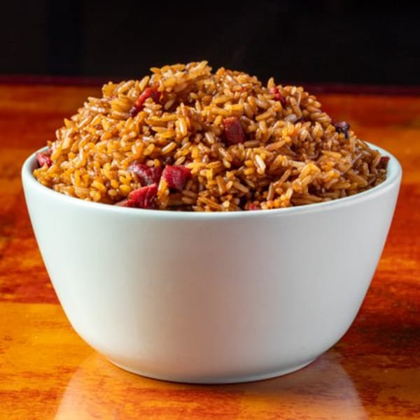 A white bowl filled with Chow n Joy's Chinese fried rice, featuring red pork pieces.